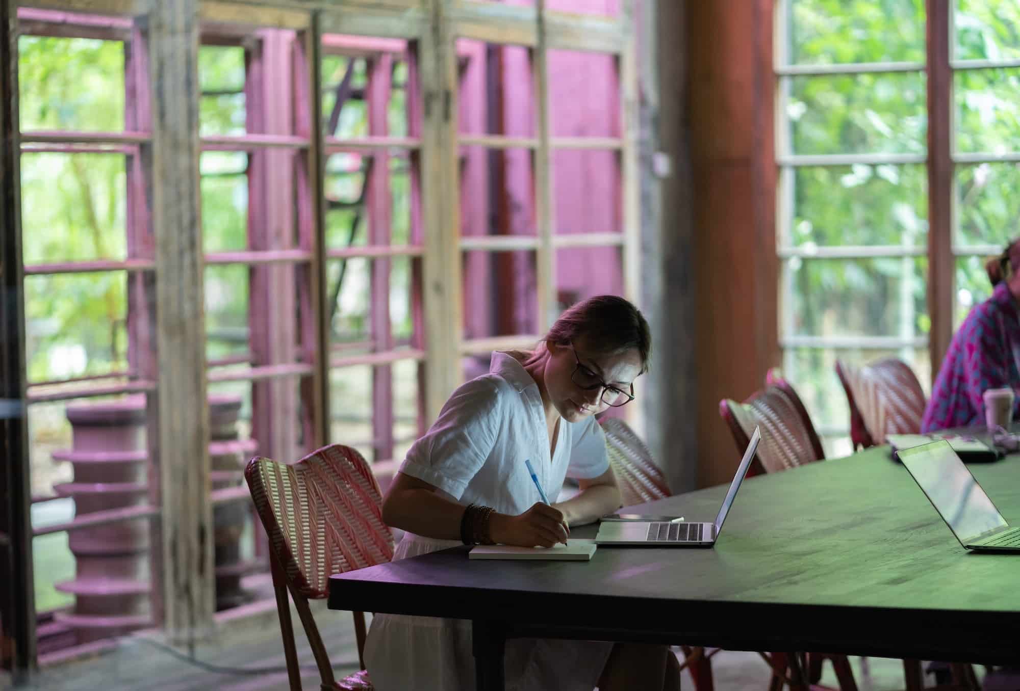 Giovane donna o studente focalizzata che prende appunti, usa il laptop, impara le lingue straniere