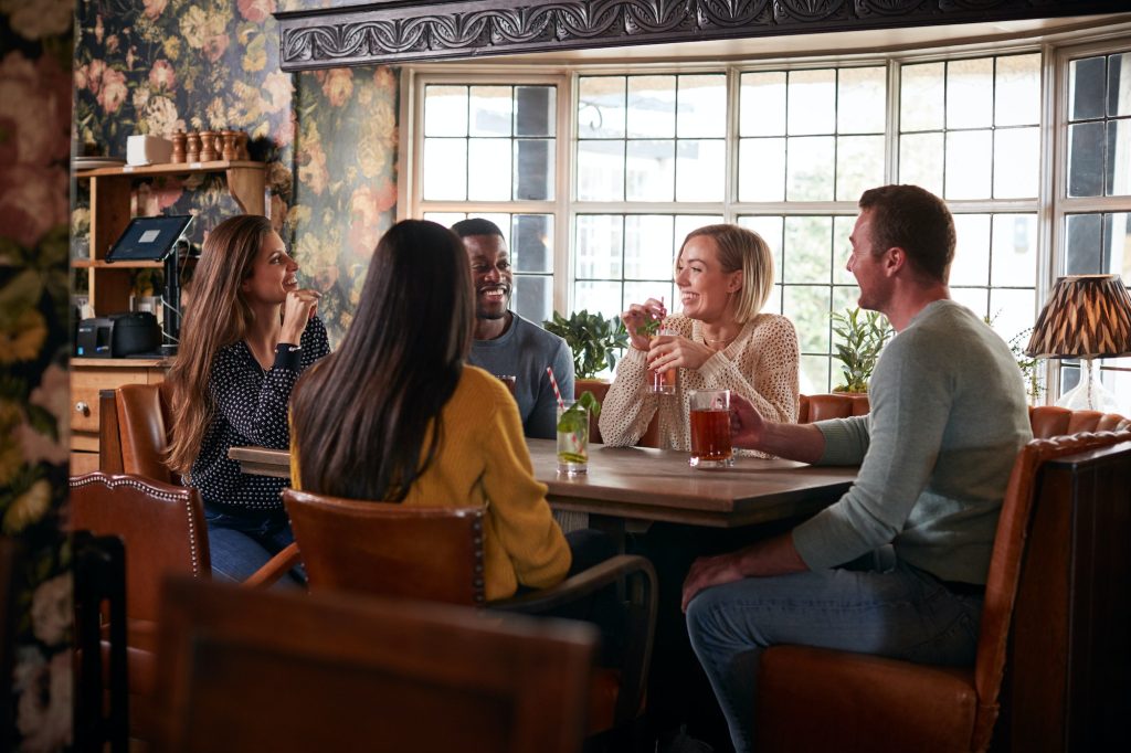 Gruppo di amici che si incontrano per un drink all'ora di pranzo nel tradizionale pub inglese