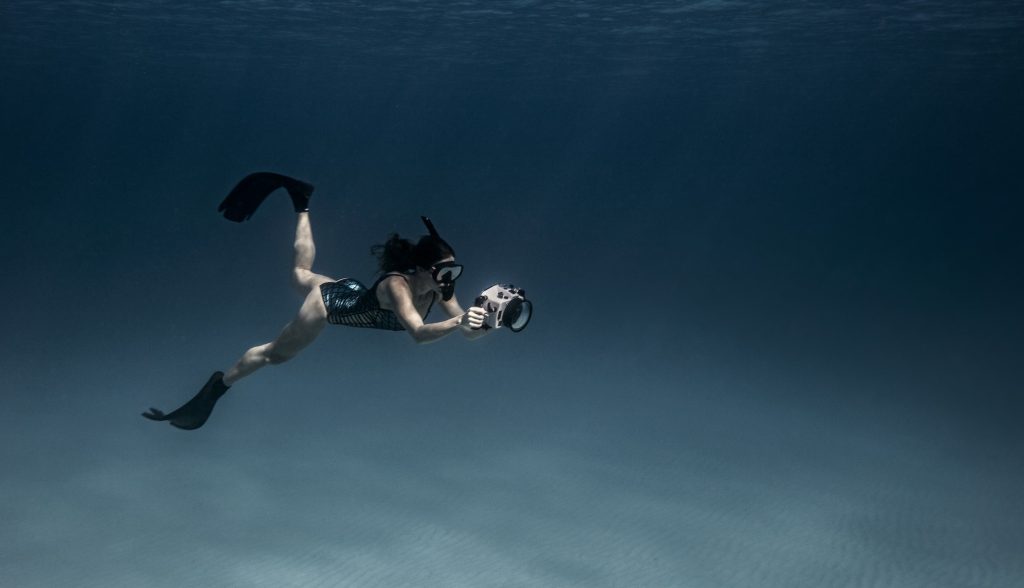Vista subacquea di una ragazza in apnea con fotocamera