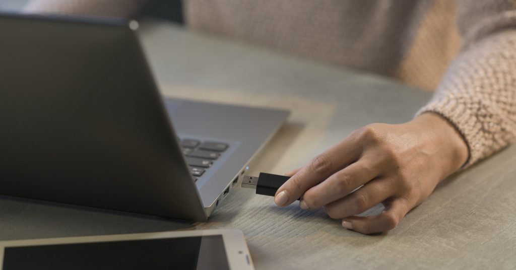 Donna che collega un'unità flash USB al suo computer portatile